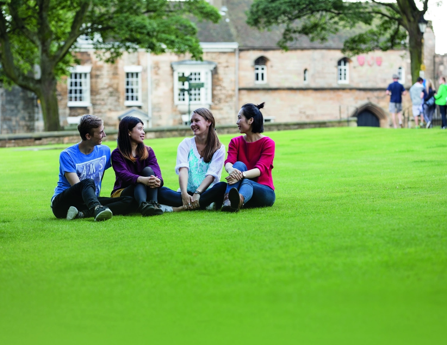Group of 4 students sitting on grass.